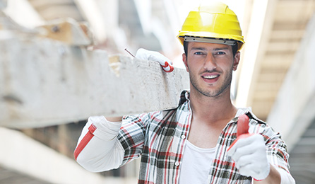 Ein Bauarbeiter mit Helm trägt ein Brett.